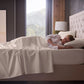 Malouf Classic Cotton Sheet Set featuring smooth, white cotton sheets and pillowcases laid out on a bed.