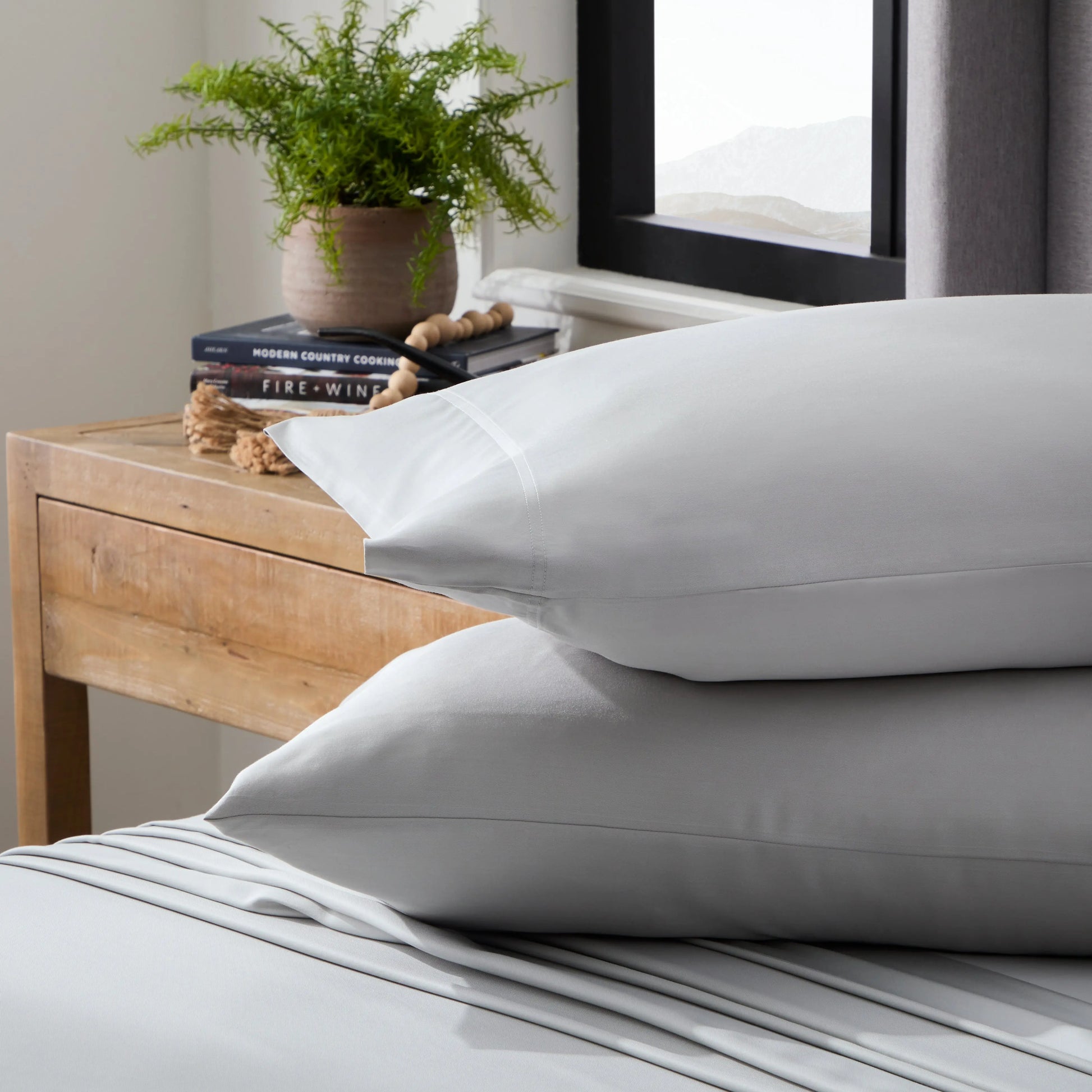 Smooth bamboo rayon sheet set by Malouf featuring soft, lightweight, ash-colored bed sheets with a neatly made bed.