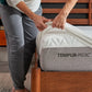 Person placing a TEMPUR-Protect mattress protector on a bed, showcasing the Tempur-Pedic bedding accessory.