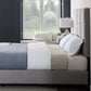Malouf Scoresby headboard in a dark fabric with a modern, tufted design and wide profile, shown in a bedroom setting