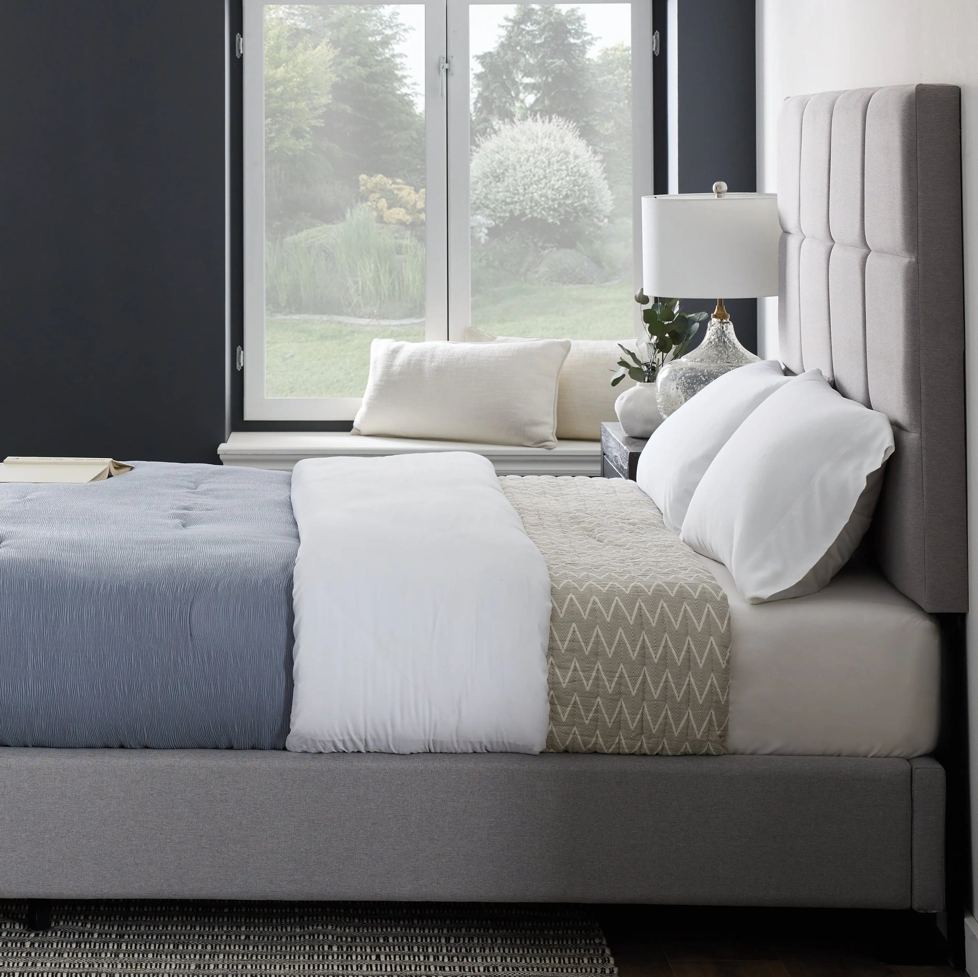 Malouf Scoresby headboard in a dark fabric with a modern, tufted design and wide profile, shown in a bedroom setting