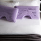 Malouf Shoulder Zoned Dough Pillow with lavender cover, showing ergonomic design and plush comfort in a lifestyle setting.